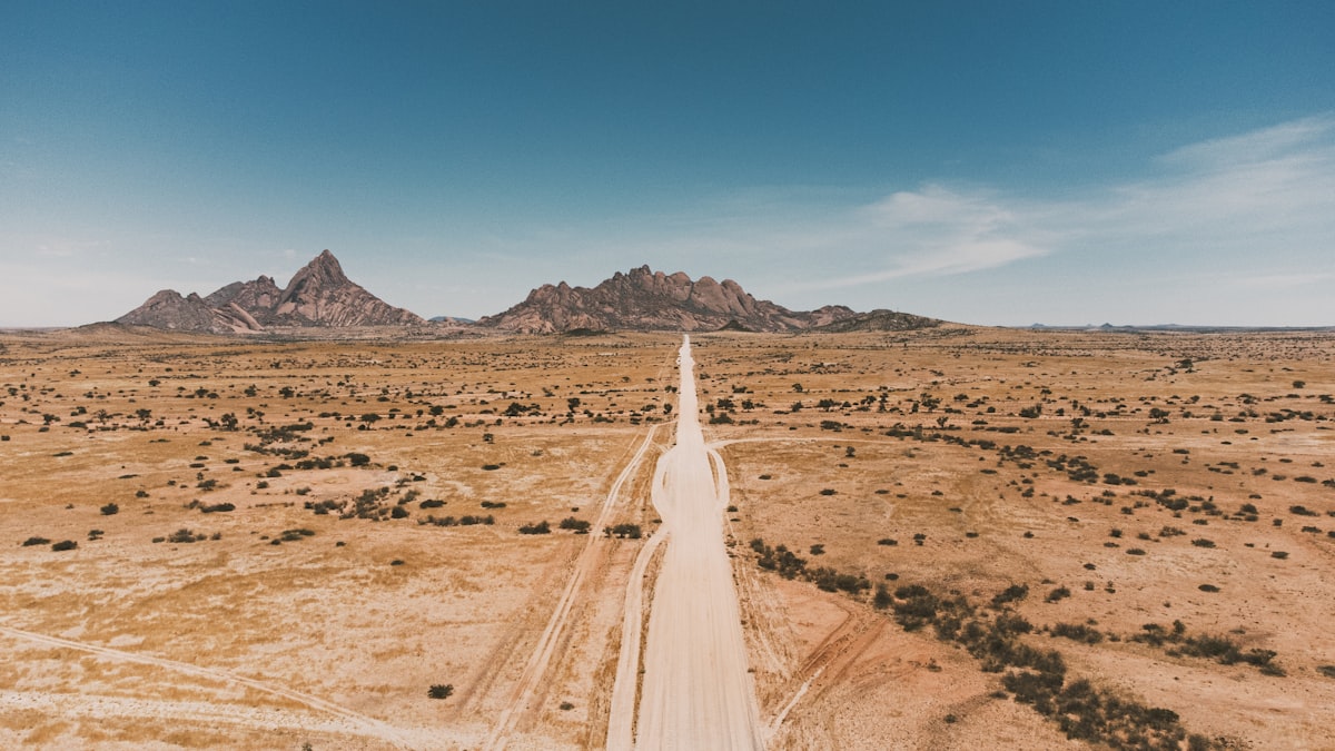 Long desert road leading to distant mountains under blue sky