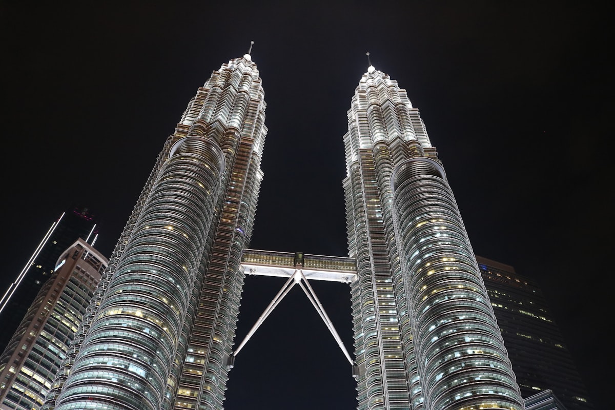 two very tall buildings towering over a city at night