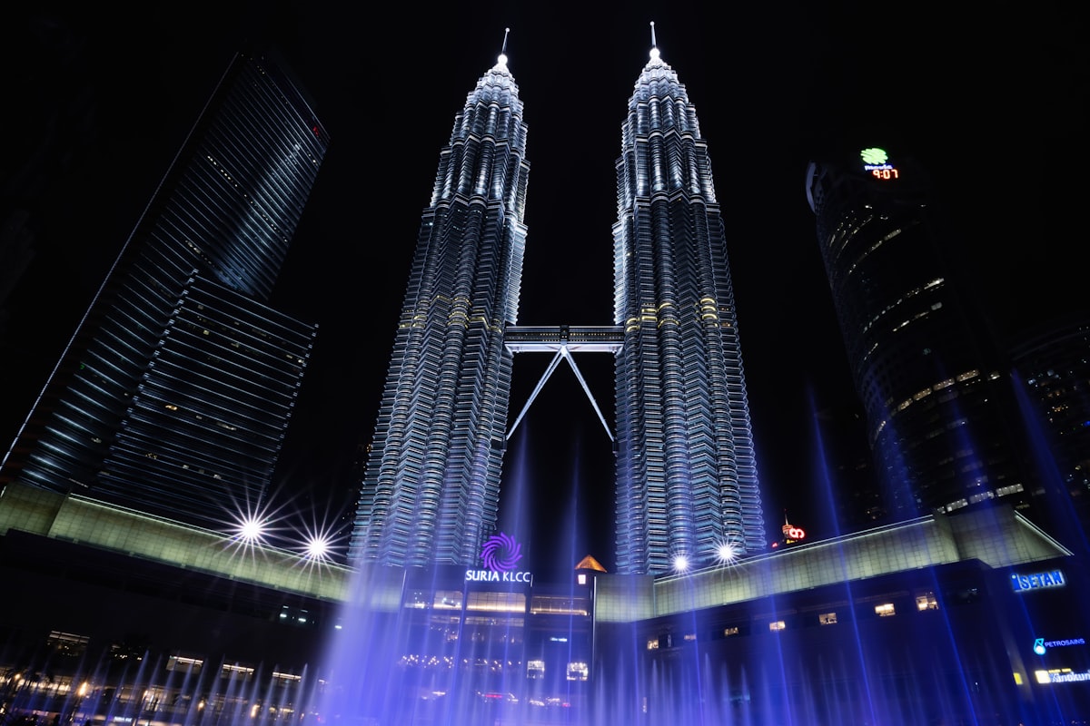 Petronas towers illuminated at night with fountain show.