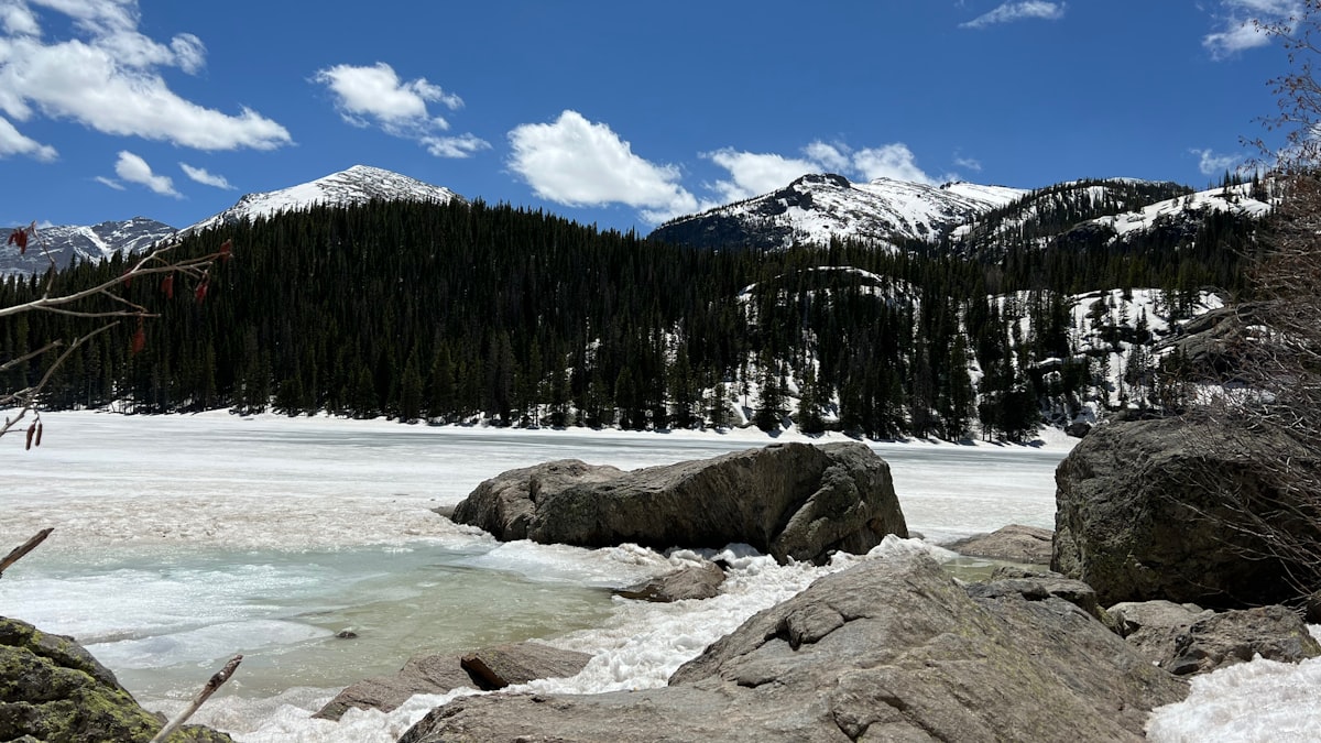 a snowy mountain with a frozen lake in the foreground