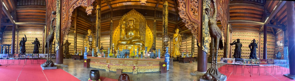 Golden buddha statue surrounded by smaller figures in temple