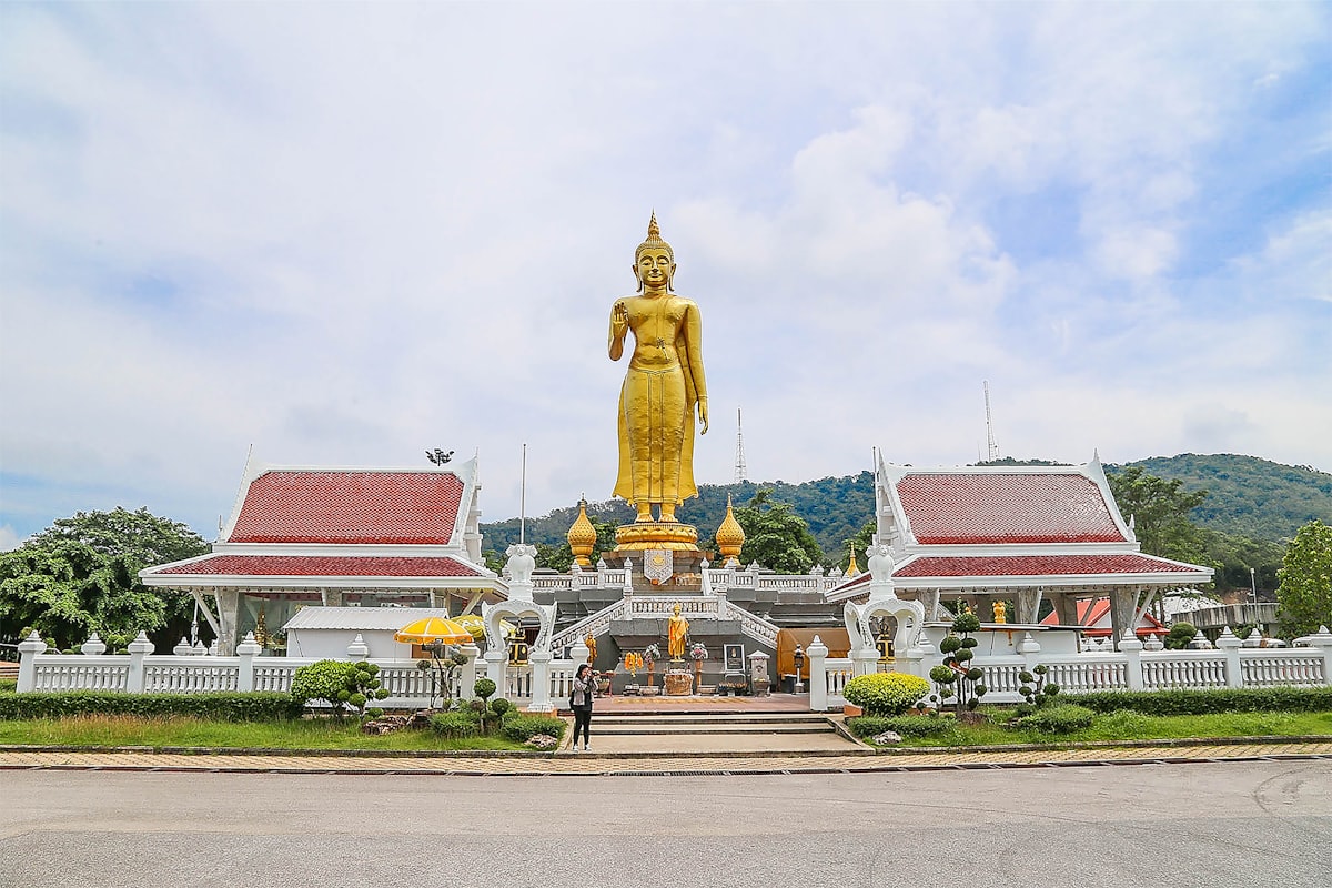 a large golden buddha statue sitting in front of a building