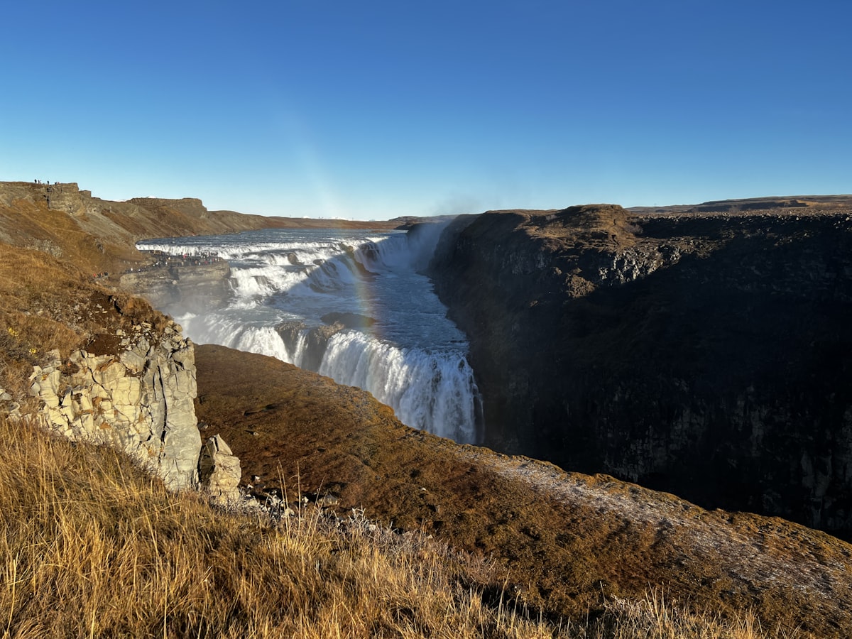 Majestic waterfall cascades through rugged canyon under clear blue sky