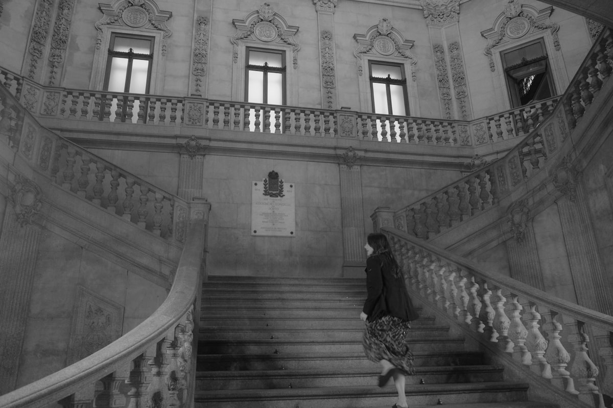 A person ascends a grand, ornate staircase in a building.