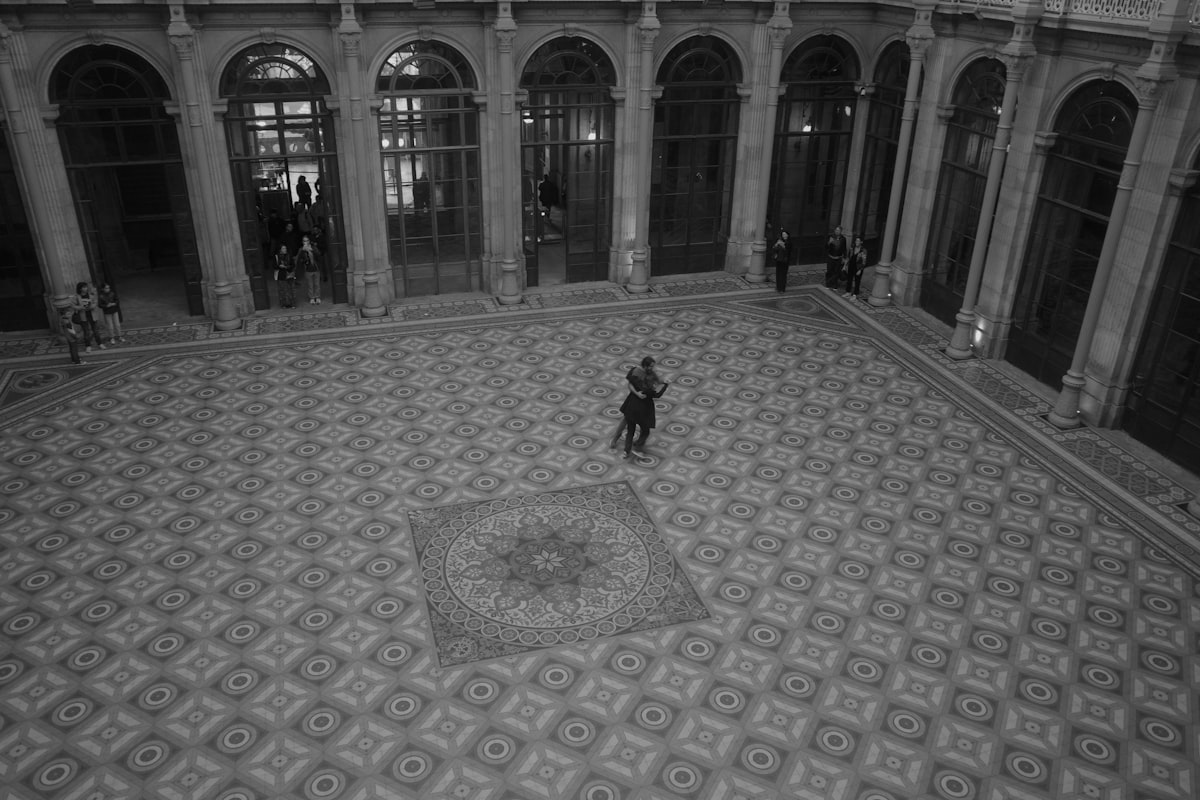 A person stands alone in a large, ornate courtyard.