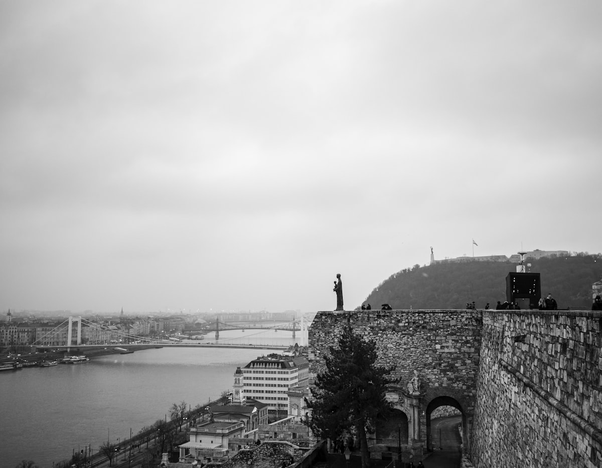 Person standing on a stone wall overlooking a river.