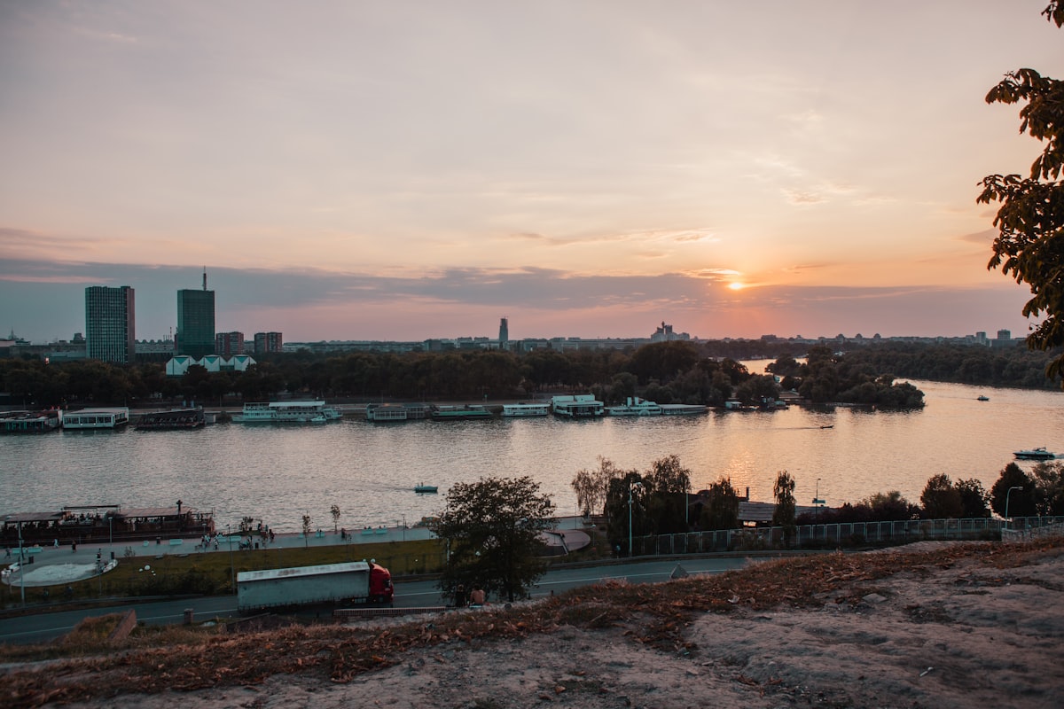 body of water near city buildings during sunset