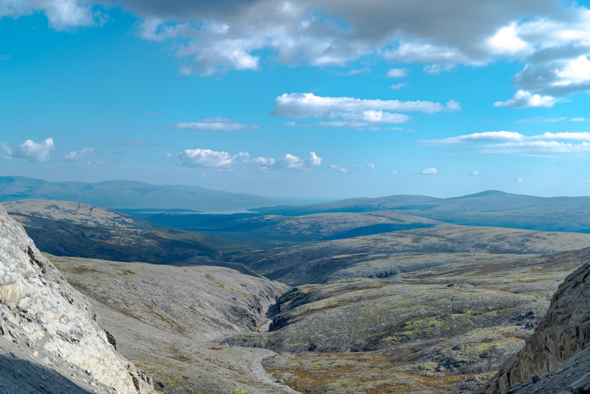 A man standing on top of a mountain next to a lush green hillside