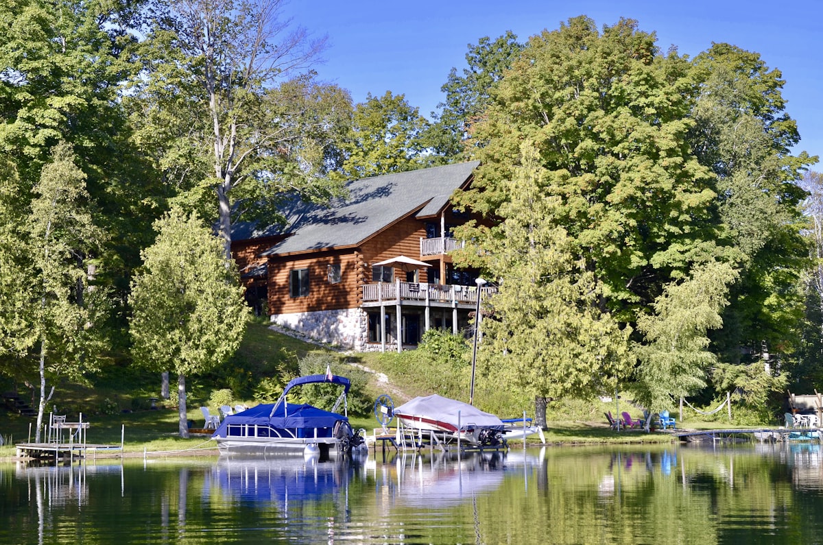 brown and white house near green trees and lake during daytime