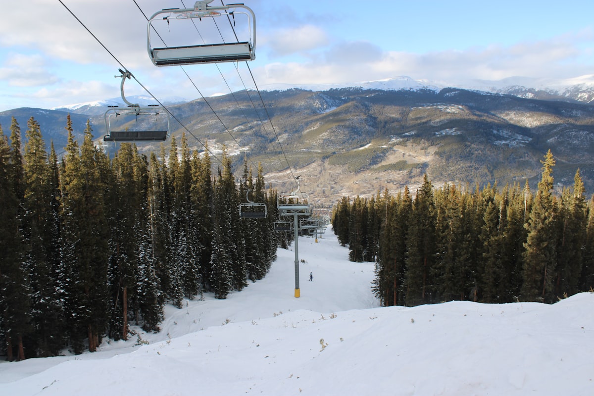 Ski lift chairs ascend a snowy mountain slope.