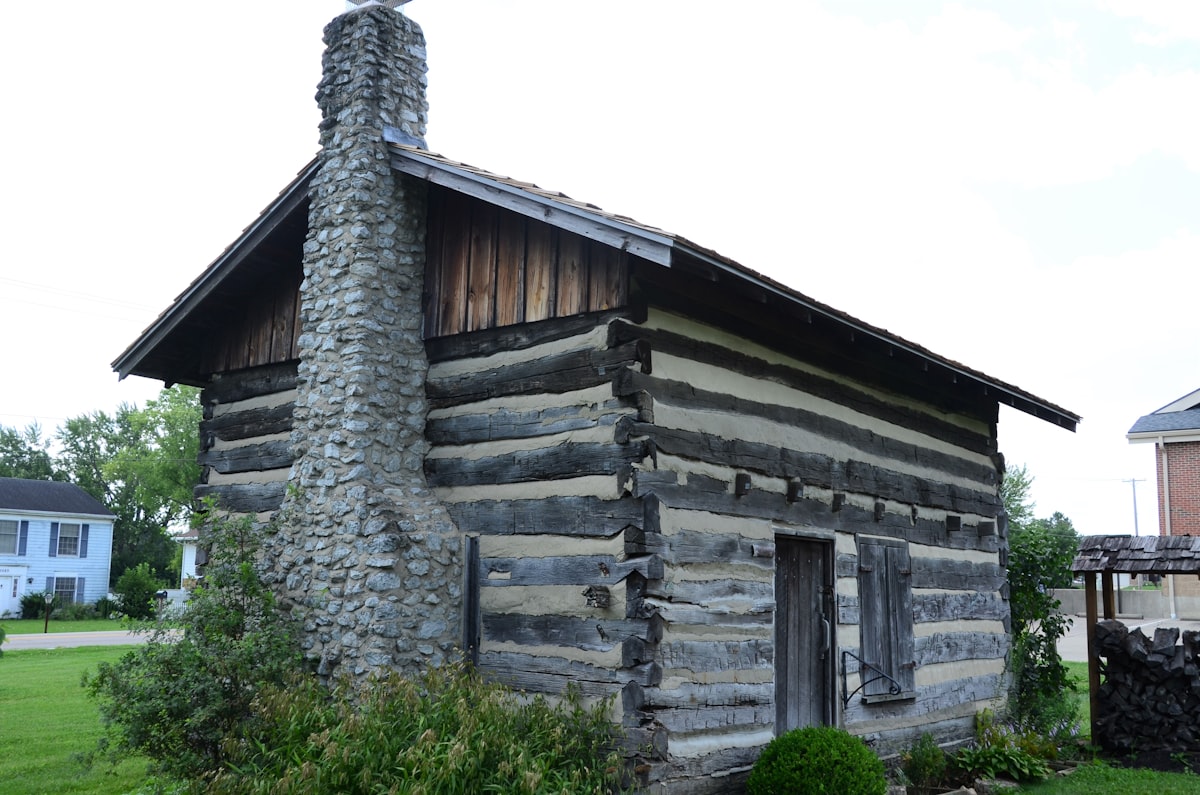 an old log cabin with a chimney and a door