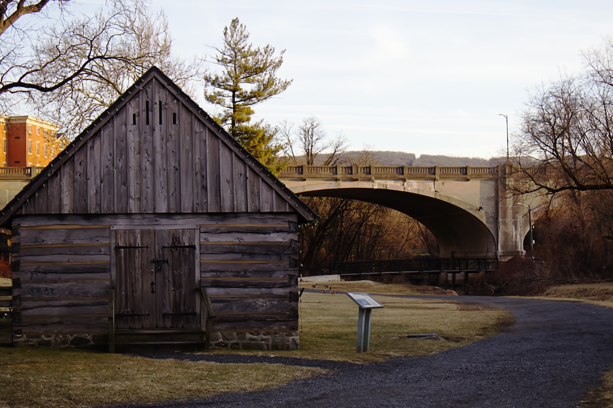 A wooden cabin sits near a bridge.