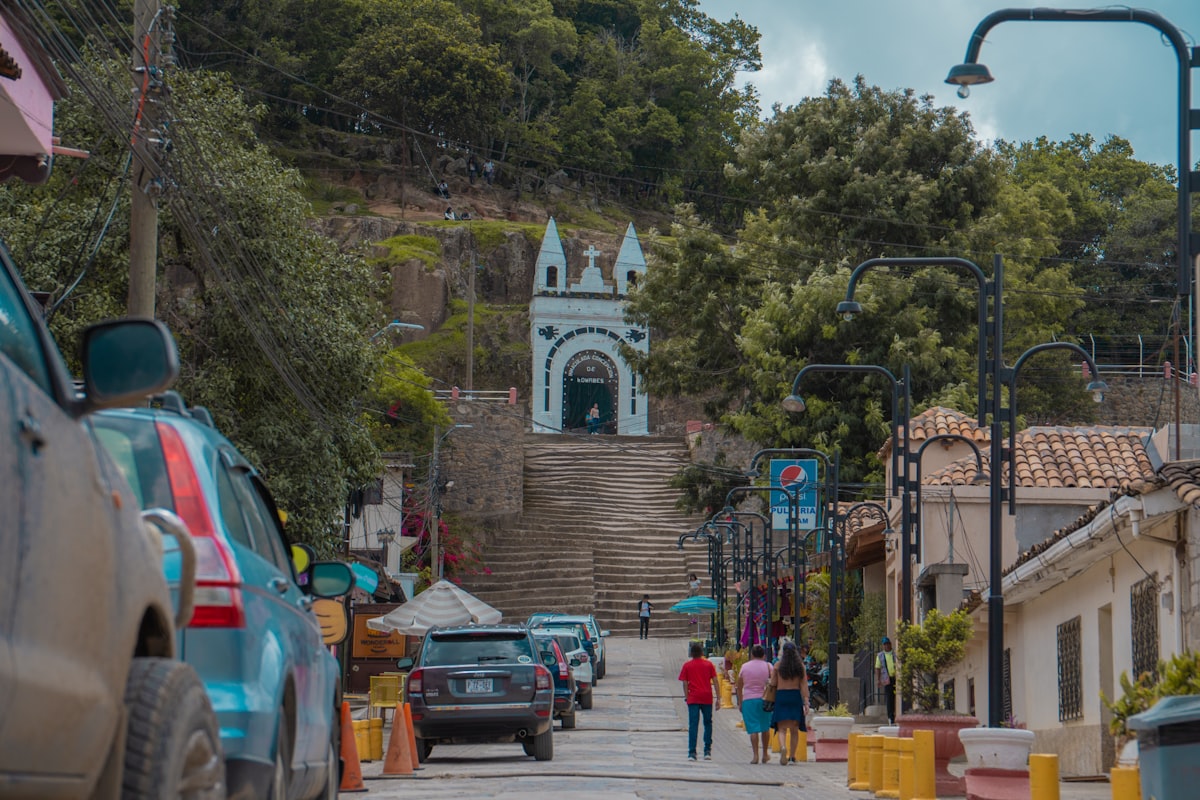 A group of people walking down a street next to parked cars