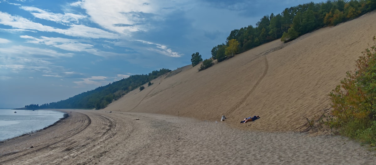 a group of people sitting on top of a sandy beach