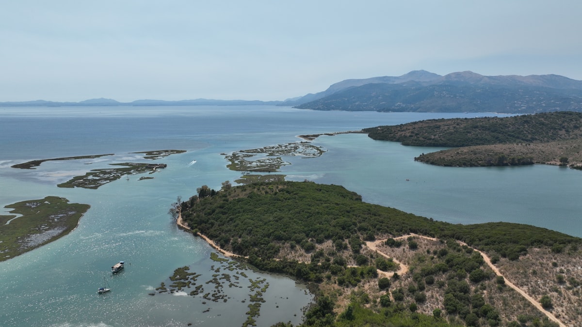 Coastal landscape with calm blue water and distant mountains.