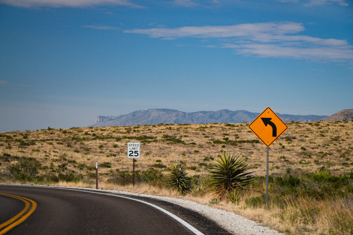 Winding road through a desert landscape with mountains.