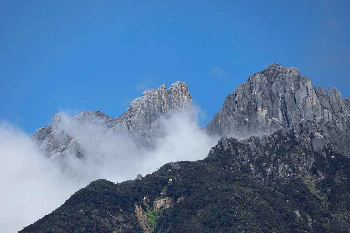 Jagged mountain peaks shrouded in mist under blue sky