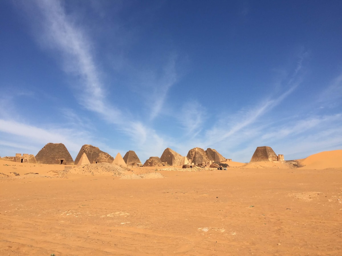 Ancient pyramids stand in a vast desert landscape.