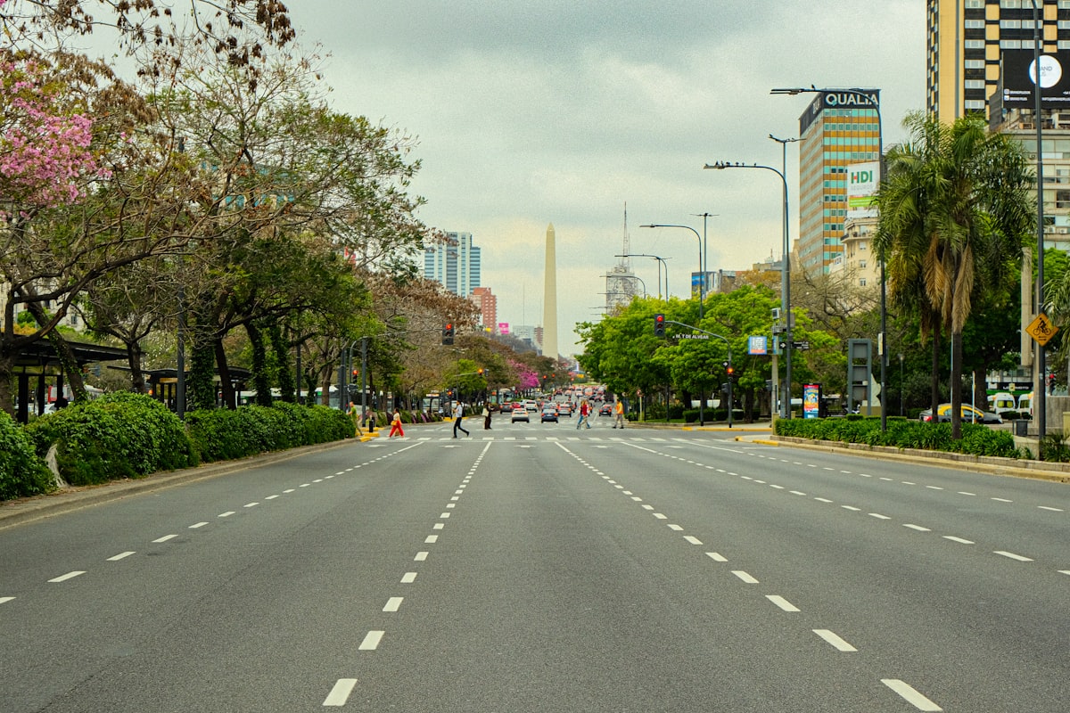 An empty street with trees and buildings in the background