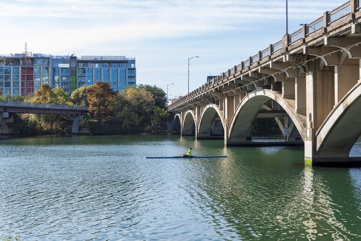 a person rowing a boat under a bridge