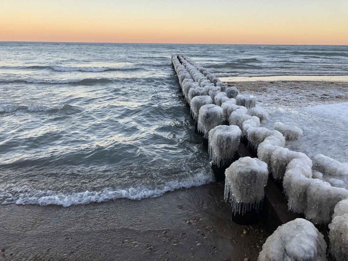 a long line of ice - covered posts on the shore of a beach