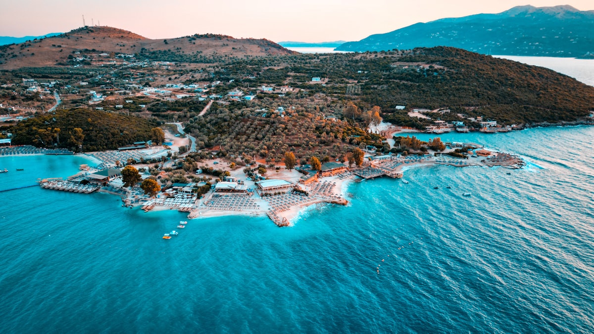 Coastal town with blue water and distant hills.