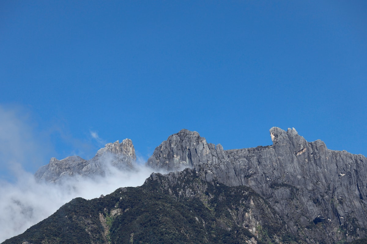 Jagged mountain peaks shrouded in mist under blue sky