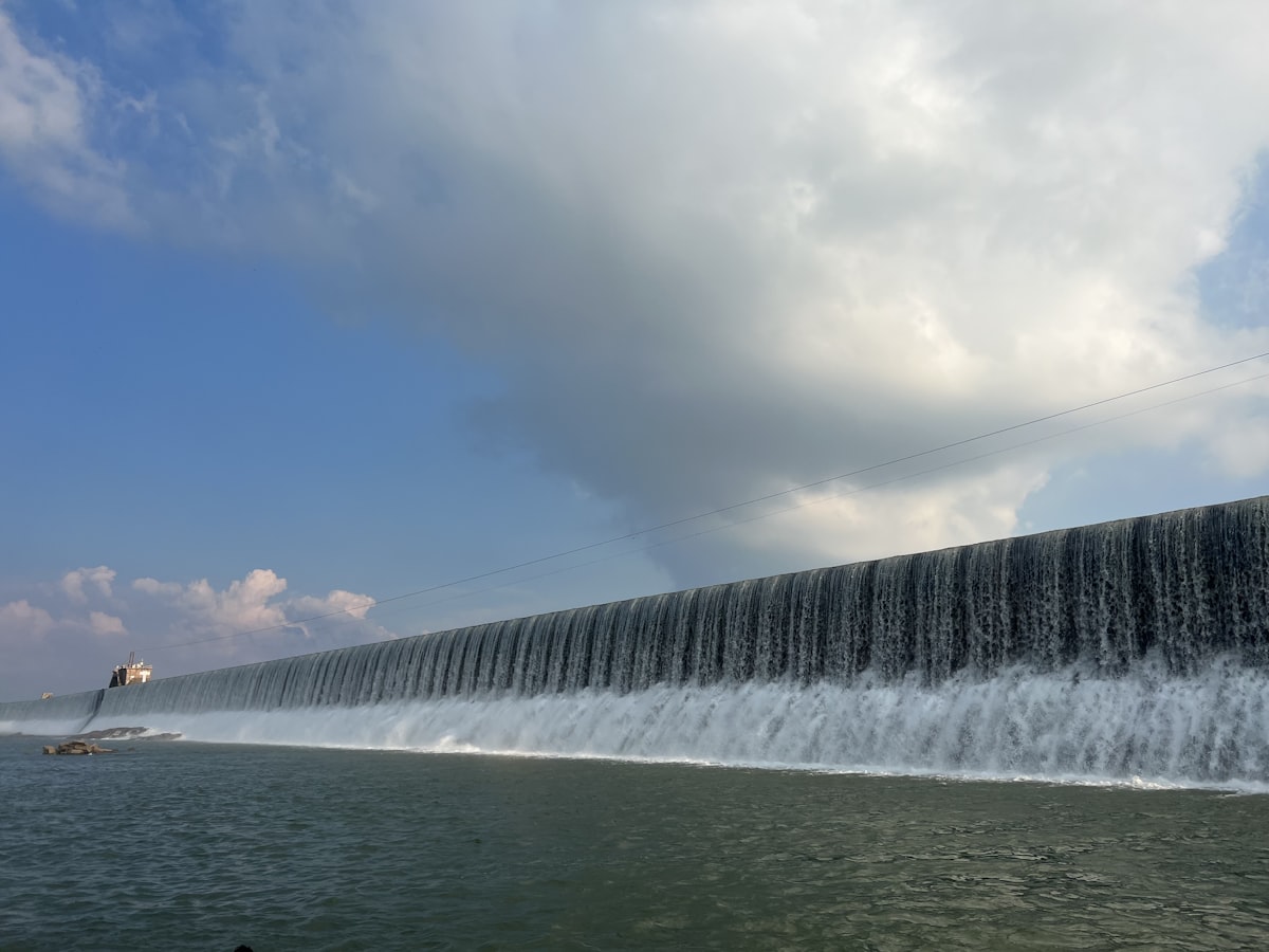 a large wall of water with a boat in the background