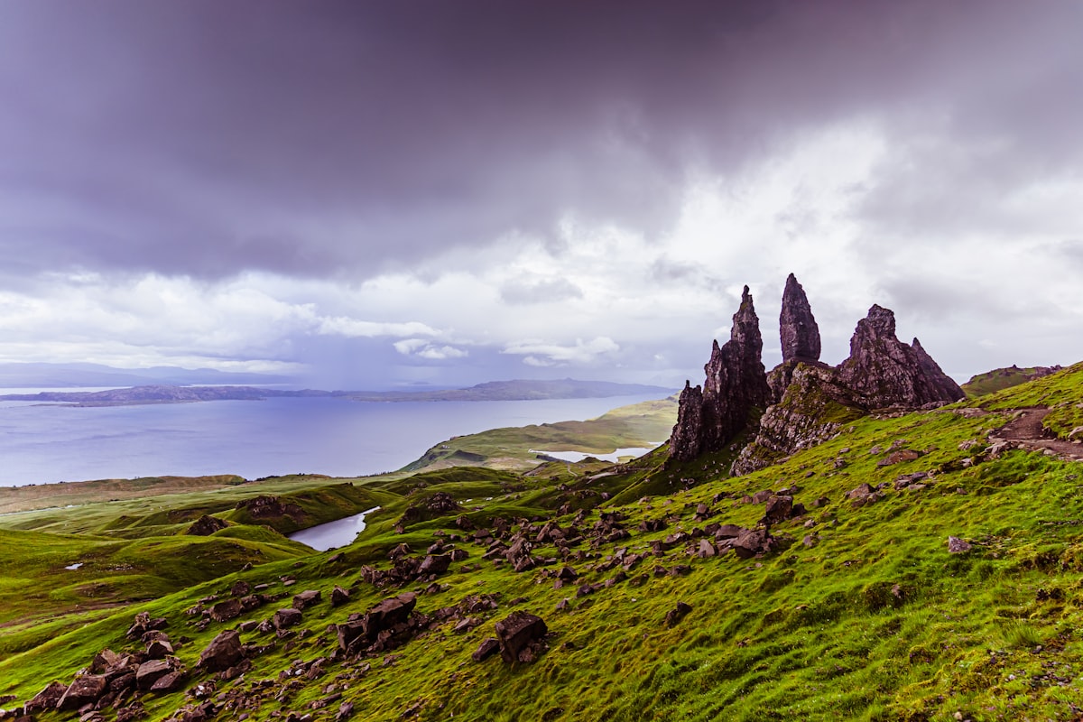 Dramatic rock formations on a green hillside overlooking the sea.