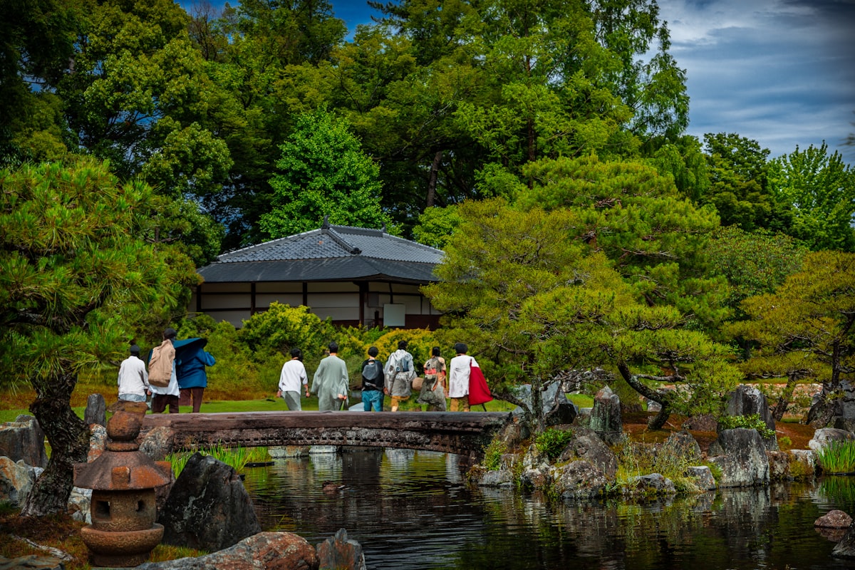 a group of people walking across a bridge over a pond