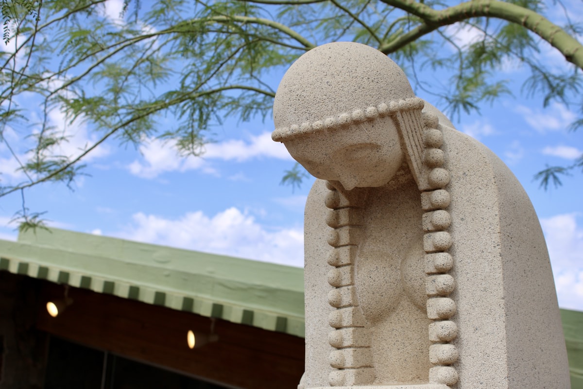 Stone statue of a woman with beaded headdress.