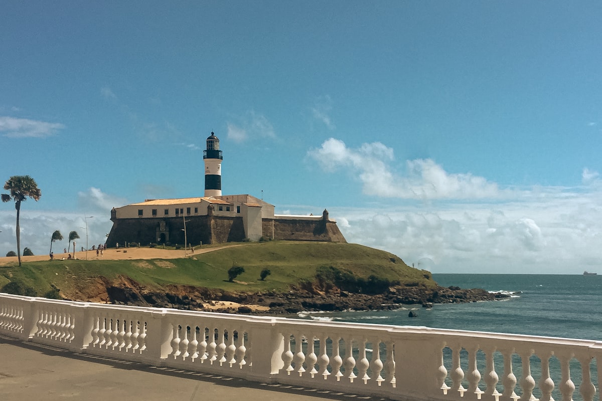 a lighthouse on top of a hill next to the ocean