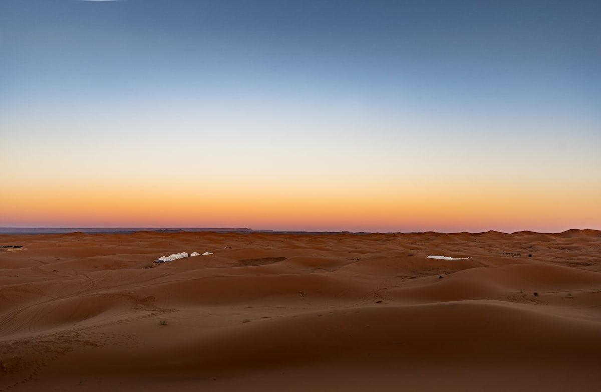 Desert sand dunes under a gradient sky at sunset